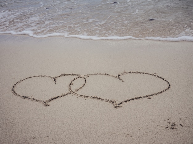 Deux Forme Coeur écrit Sur La Plage De Sable Avec Des Vagues