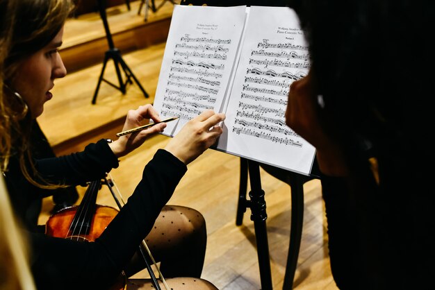 Deux musiciennes corrigeant une partition avec un crayon avant que l'orchestre ne commence à jouer. Photo Premium
