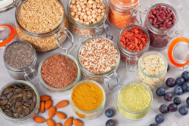 Différents superaliments aux baies de goji, quinoa, chia, graines de chanvre, graines de lin, pois chiches, avoine, amande, myrtilles, curcuma, matcha et lantilles. végétalien, végétarien, concept de produits bio régime diététique Photo Premium