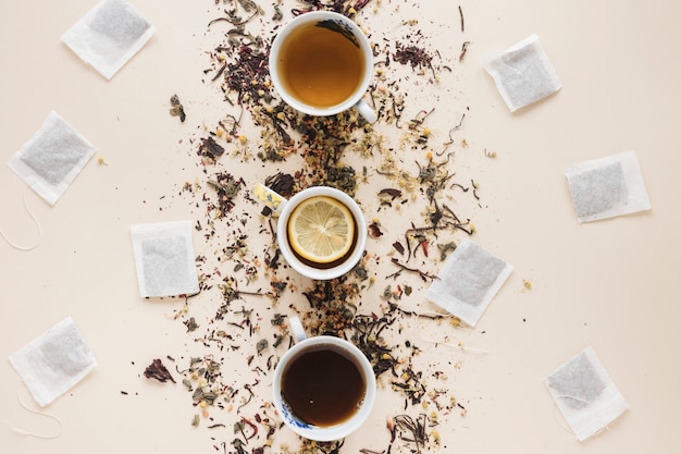 Différents types de thé disposés dans une rangée avec un sachet de thé et des herbes sur un fond coloré Photo gratuit
