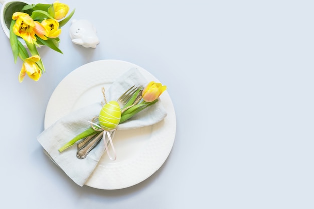 Dîner de pâques réglage de la table avec une tulipe jaune sur la table. vue de dessus. Photo Premium