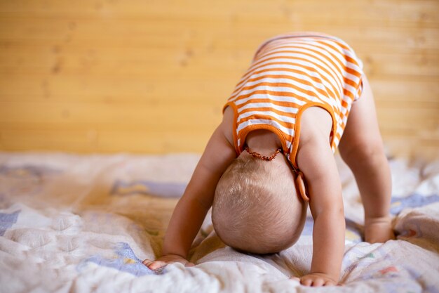 Un Drole De Jouer Bebe Mignon Dans Le Collier Bebe Ambre Essayant De Se Lever En Faisant Des Exercicesm Stading Sur Sa Tete Et Les Mains Dos A L Avant Photo Premium