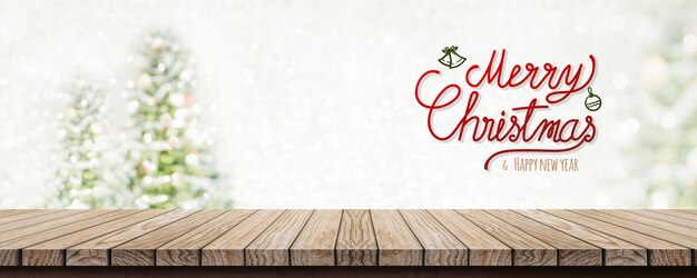 Écriture joyeuse noel et bonne annee sur table en bois avec flou arbre de noel un Photo Premium