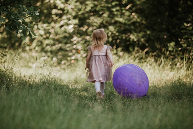 Elegante Petite Fille 2 5 Ans Tenant Le Gros Ballon Vetue D Une Robe Rose Tendance Dans Prairie Espiegle Fete D Anniversaire Petite Fille Avec Un Ballon Dans Le Parc Photo Premium