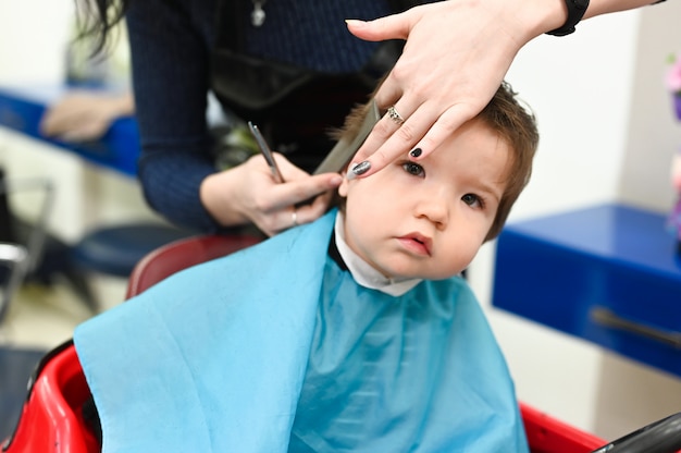 Un Enfant Chez Le Coiffeur La Premiere Coupe De Cheveux De L Enfant Chez Le Coiffeur Bebe Coupe De Cheveux Enfant En Bas Age Photo Premium