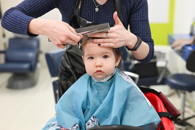 Un Enfant Chez Le Coiffeur La Premiere Coupe De Cheveux De L Enfant Chez Le Coiffeur Bebe Coupe De Cheveux Enfant En Bas Age Photo Premium