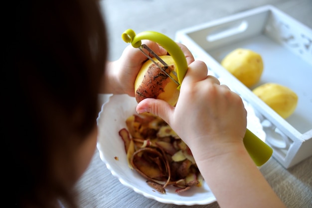 L'enfant épluche Les Pommes De Terre Avec Un éplucheur ...