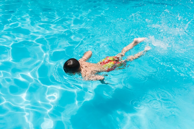 Enfant nageant dans la piscine Photo gratuit