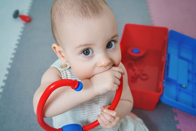 L Enfant Ronge Un Jouet Le Bebe Joue Avec Un Ensemble De Medecins Petit Enfant Essaie De Jouer Avec Un Phonendoscope Photo Premium