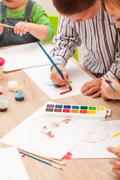 Les Enfants Apprennent A Peindre Avec Un Pinceau Et Des Aquarelles Sur Papier A La Maternelle Photo Premium