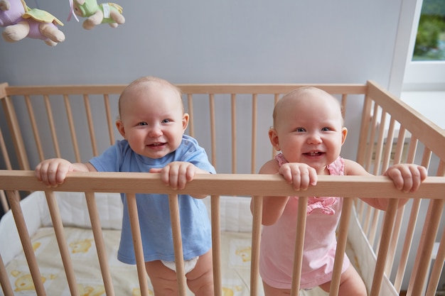 Enfants Jumeaux Garcon Et Fille Sourient En Se Tenant Debout Dans Le Berceau Photo Premium