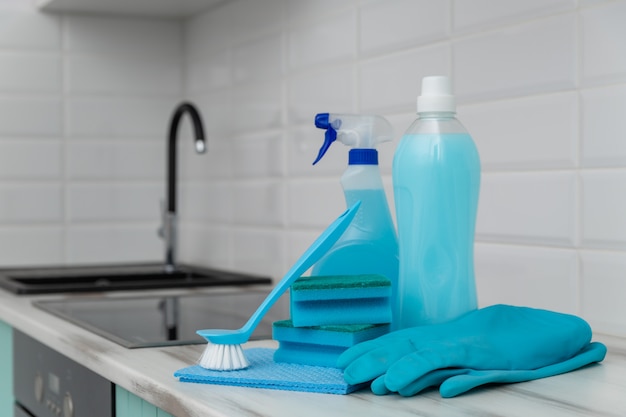 Un ensemble de produits de nettoyage bleus et d’outils de nettoyage se trouve sur la table de la cuisine. Photo Premium
