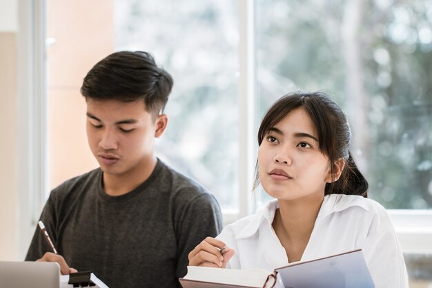 Étudiant asiatique note sur le cahier tout en apprenant à étudier et à écrire pour planifier le travail. Photo Premium