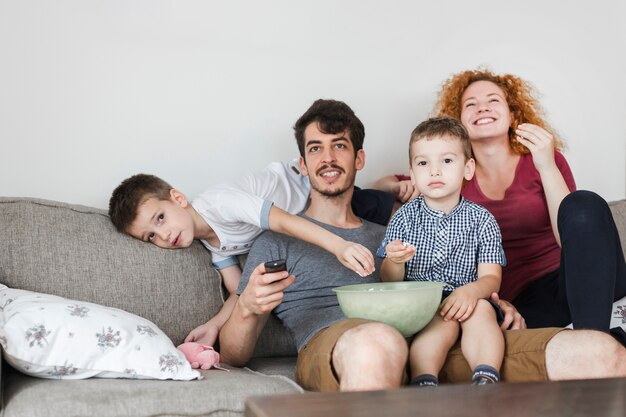 Famille Assise Sur Un Canape Devant La Television A La Maison Photo Premium