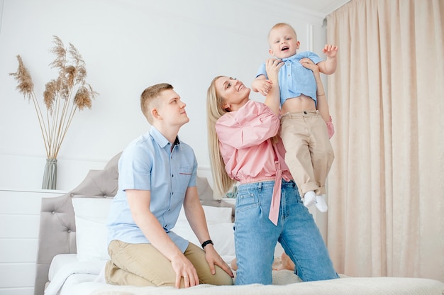 Famille Heureuse Avec Un Bebe Mignon Maman Papa Fils Jouent Sur Le Lit Dans Une Piece Lumineuse Et Confortable A La Maison Photo Premium