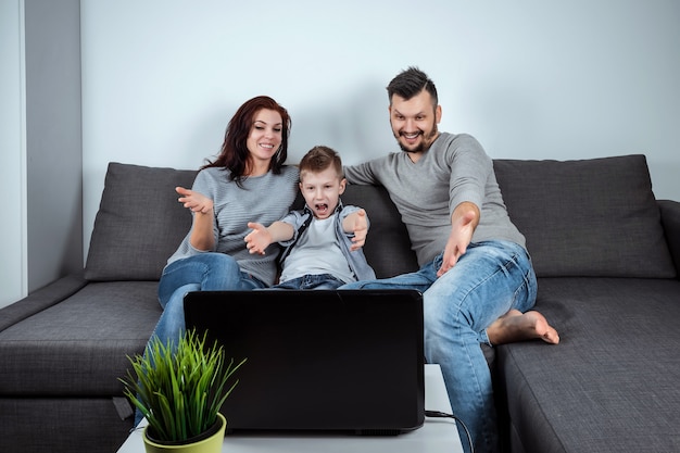 Une famille heureuse sourit en regardant quelque chose dans un ordinateur portable Photo Premium