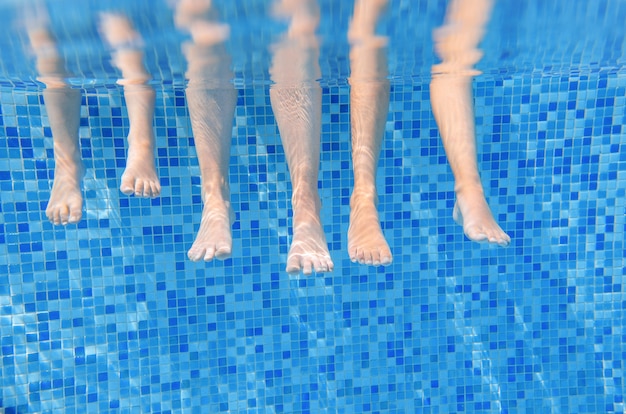 Famille jambes sous l'eau dans la piscine, nager avec les enfants sous l'eau concept drôle, sport et vacances avec les enfants Photo Premium