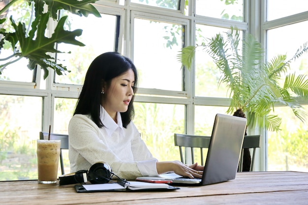 Femme d'affaires, charmante peau beige belle entreprise asiatique femme chic main travailler sur ordinateur portable dans la maison de verre. Photo Premium