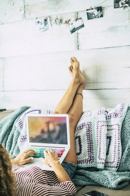 Femme Allongée Sur Le Canapé Avec Les Jambes Posées Sur Le Mur Se Détend En Regardant L