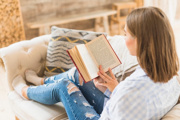 Femme Assise Sur Canapé Avec Livre De Lecture Photo Gratuite 