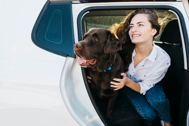 Femme assise avec son chien dans le coffre ouvert Photo gratuit