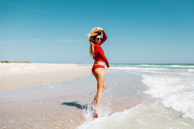 Femme Blonde Voyageuse Sautant Avec Une Expression Heureuse Se Retourne Dans L Eau Porter Un Bikini Rouge Toute La Longueur Vacances D Ete Photo Gratuite