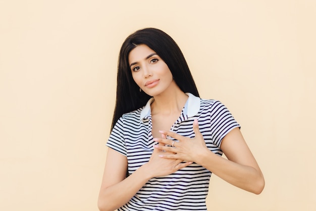 Une femme brune à la recherche amicale garde la main sur le cœur comme elle le dit Photo Premium