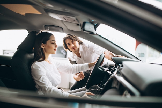 Femme choisissant une voiture dans une salle d'exposition Photo gratuit