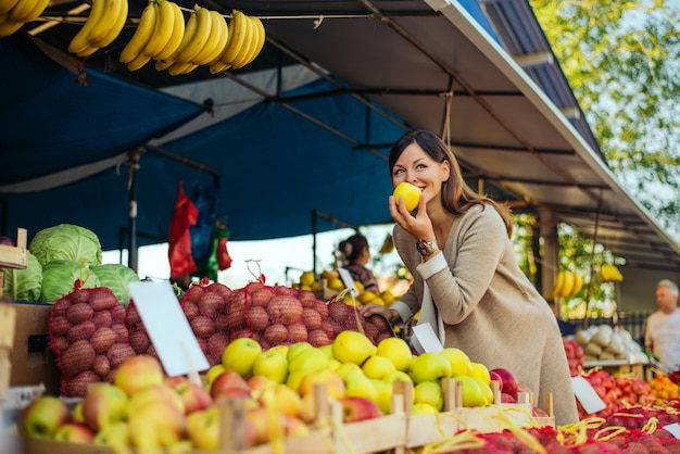 Femme dans un marché au rayon des fruits pour acheter des fruits, elle vérifie les pommes. Photo Premium