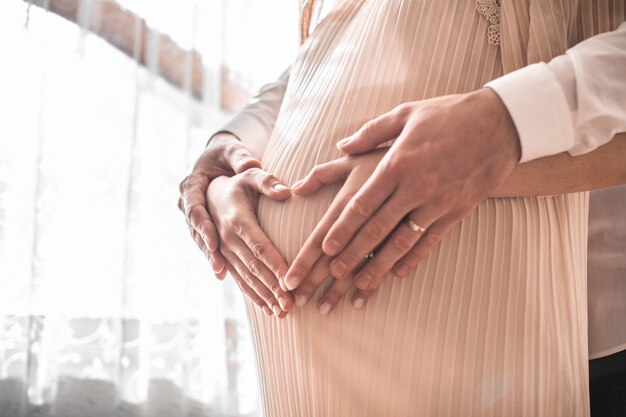 Femme Enceinte Et Son Mari Tenant La Main En Forme De Coeur Sur La Bosse De