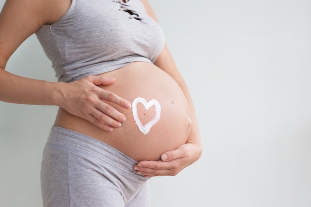 Femme Enceinte Tenant Coeur Rouge Et La Main Sur Son Ventre Symbole D Une Nouvelle Vie Concept D Attendre Pour Bebe Et Elargir La Famille Photo Premium