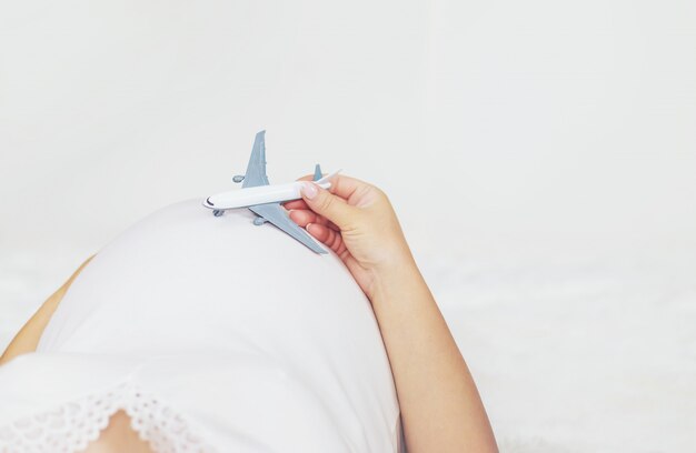 Une Femme Enceinte Tient Un Avion.  Photo Premium