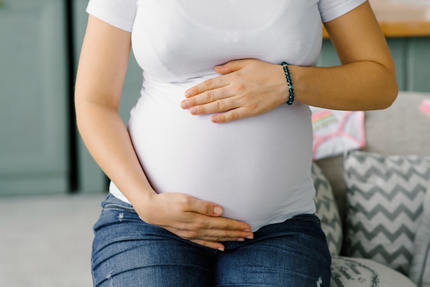 Une Femme Enceinte Tient Ses Mains Sur Son Gros Ventre En Attendant Le Bebe Photo Premium