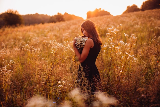 Femme Heureuse Avec Des Fleurs Se Dresse Sur Le Champ De La Soir E