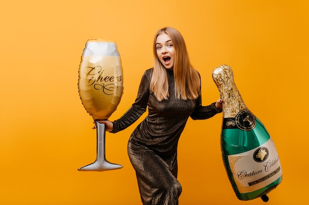 Femme Joyeuse Avec Une Coiffure Droite Exprimant Des Emotions Surprises A La Fete D Anniversaire Portrait Interieur De La Belle Femme Gracieuse Avec Une Bouteille De Champagne Et Verre A Vin Photo