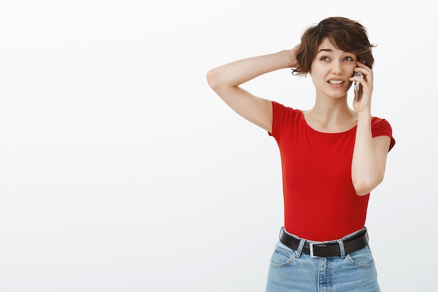 Femme Mignonne Maladroite Et Indecise Se Gratter La Tete Desemparee Tout En Parlant Au Telephone Photo Gratuite