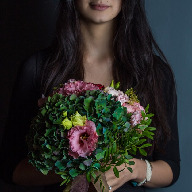 Une Femme En Noir Tenant Un Bouquet De Fleurs Vertes à La