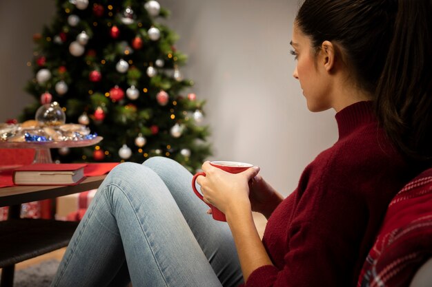 Femme regardant une tasse avec un fond de noël Photo gratuit