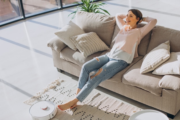 Femme Se Reposant Sur Un Canap Pendant Qu Un Aspirateur Robot Fait Le M Nage Photo Gratuite