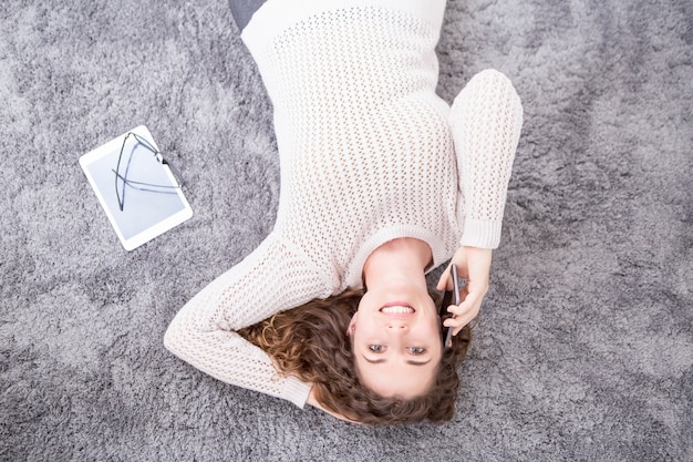 Femme Souriante Allongée Sur Le Sol Et Appelant Le Téléphone Photo Gratuite