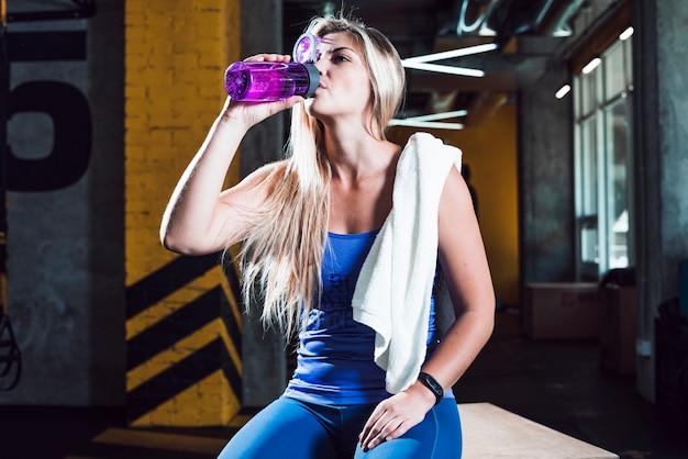 Une femme sportive buvant de l'eau en salle de sport Photo gratuit