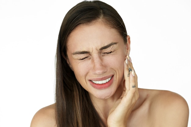 Mujer tocando el lado izquierdo de la mandíbula con rostro de dolor