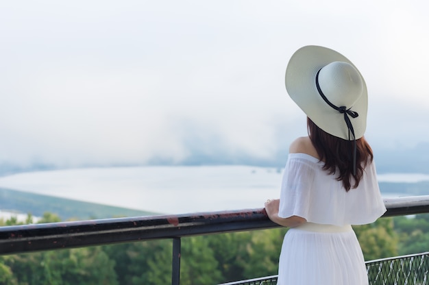 Femmes coiffées d'un chapeau à bord blanc debout pour regarder la vue. Photo Premium