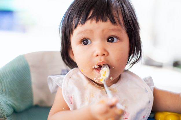 Fille Asiatique Bebe Mignon Bebe Manger Des Aliments Sains Par Elle Meme Et Faire Un Gachis Photo Premium
