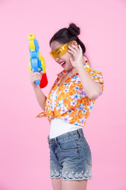 Fille Heureuse Tenant Un Pistolet à Eau De Fond Rose