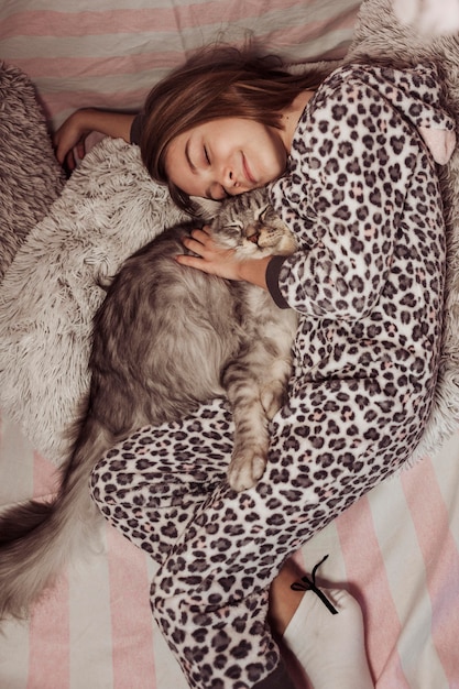 Fille En Pyjama Serrant Son Chat Et Allonge Sur Le Lit Photo Gratuite