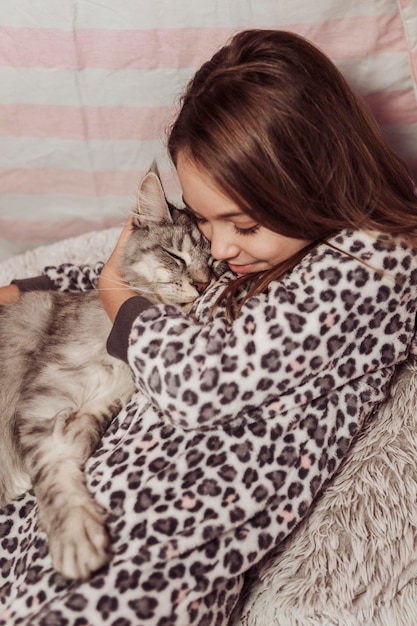 Fille En Pyjama Serrant Son Chat Moelleux Photo Gratuite