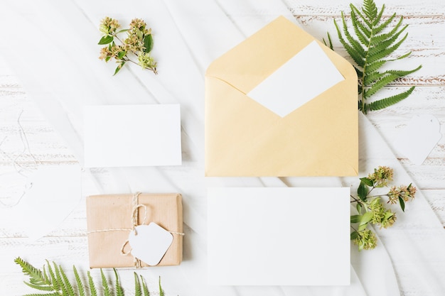 Fleurs; Fougère; Coffret Cadeau Emballé; Carte; Enveloppe Et écharpe Sur Table En Bois Photo gratuit