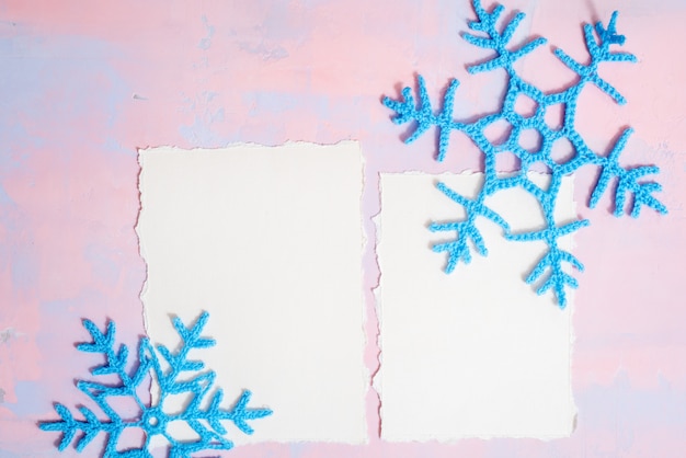 Fond de noël avec cahier vierge, flocon de neige au crochet bleu, fait à la main sur un fond violet-rose. papier déchiré tendance. lay plat, vue de dessus. fond Photo Premium
