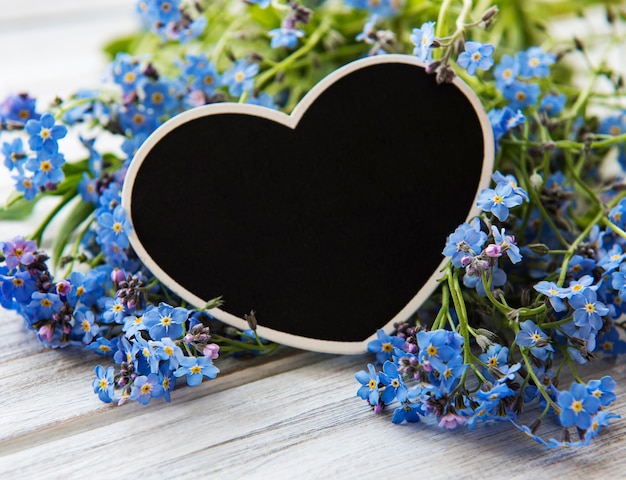 Forget Me Not Fleurs Et Planche En Forme De Coeur Noir Sur Fond De Bois Blanc Photo Premium